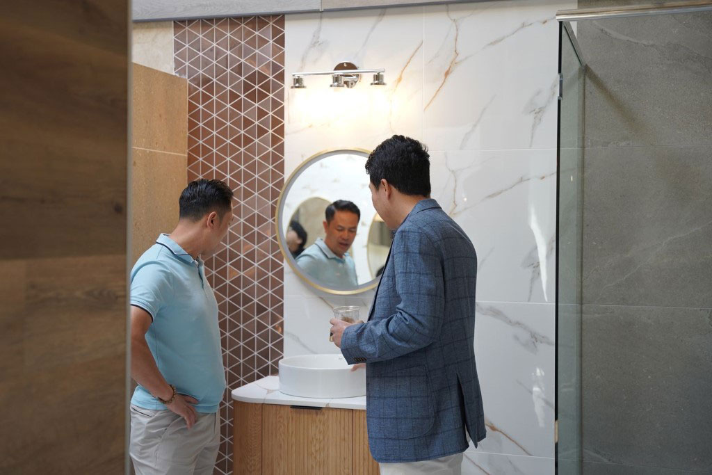 A B2B sales professional in a blazer discussing modern bathroom fixtures with a client in a showroom.