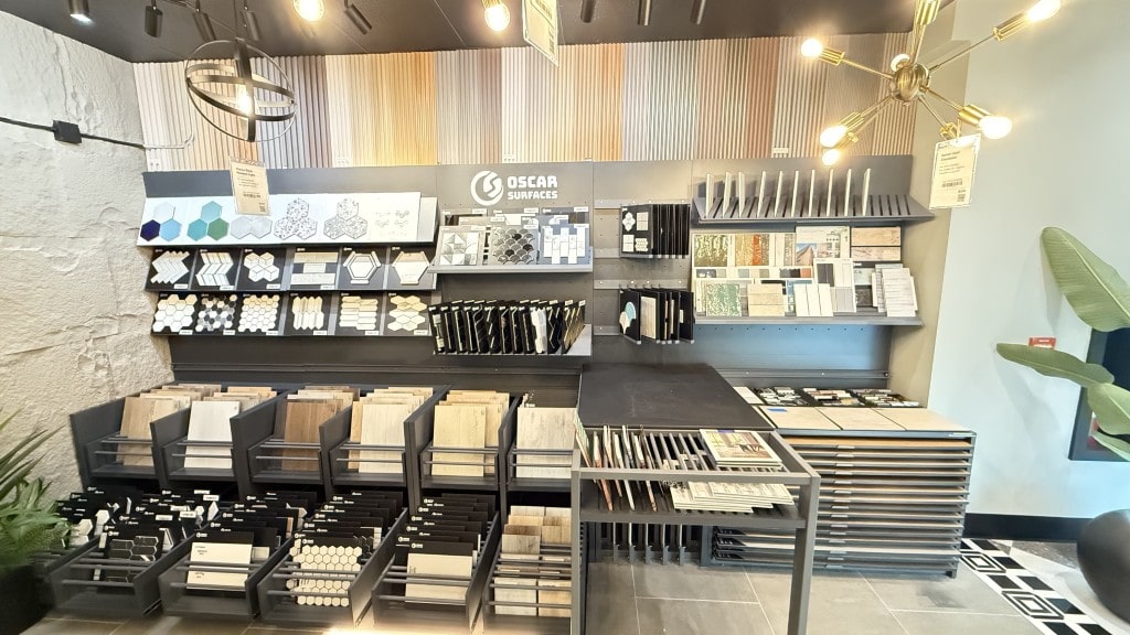 Interior of the Oscar Surfaces showroom, displaying a wide selection of tile samples on shelves and racks, including various shapes, colors, and patterns.