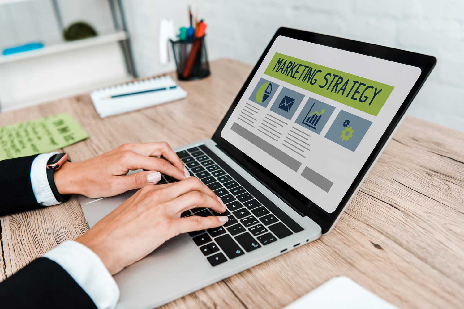 Marketer typing on a laptop showing a marketing strategy screen for Pixel Commercial Studio's B2B growth guide.