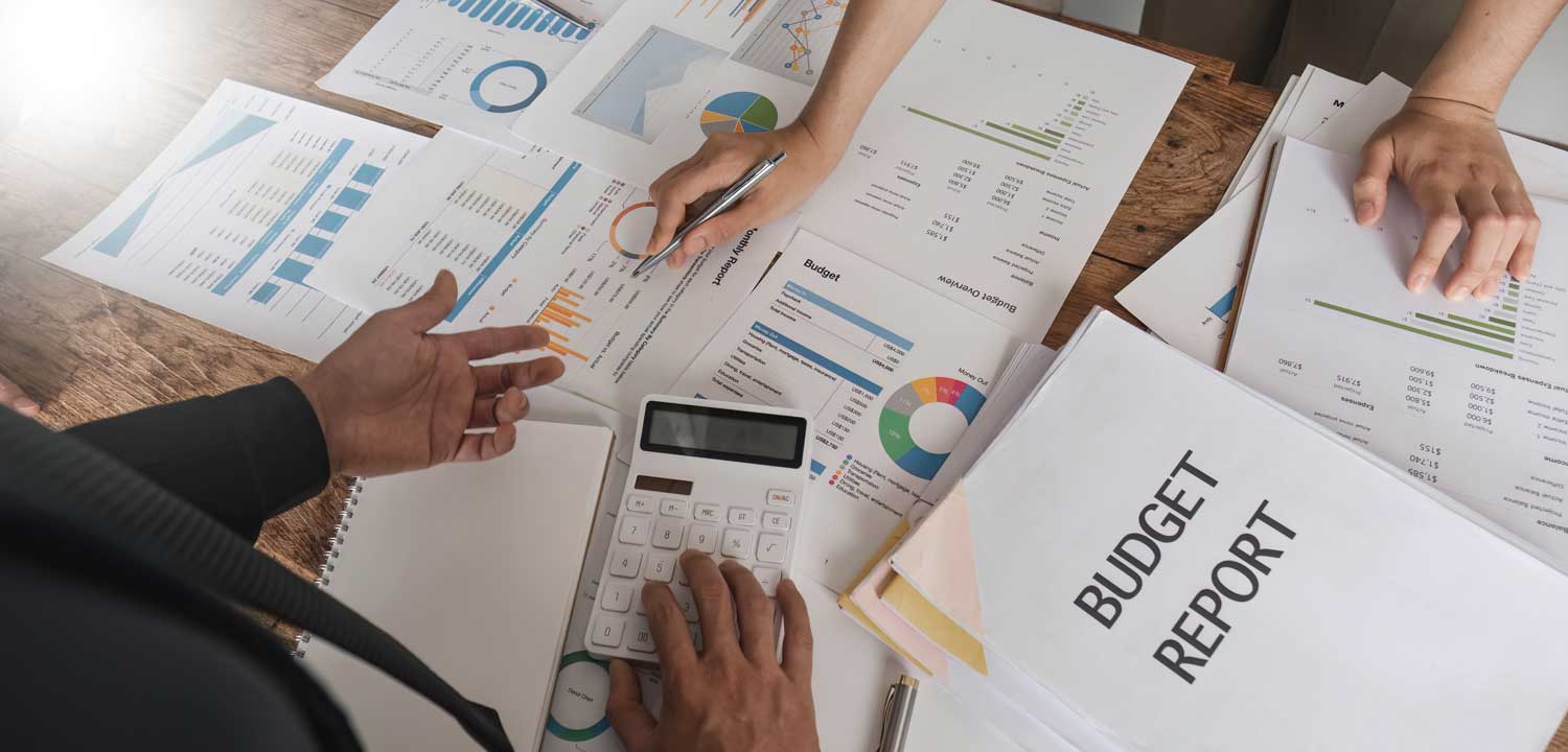 Professionals analyze a budget report and financial charts to optimize digital marketing consulting services ROI.